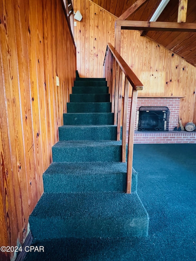 stairs featuring carpet flooring, wood walls, wood ceiling, and lofted ceiling with beams