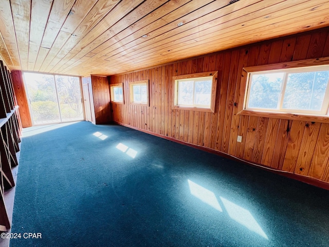 empty room with carpet, wooden ceiling, and wood walls