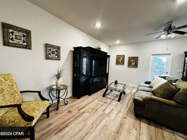 living room with hardwood / wood-style flooring, ceiling fan, and a textured ceiling