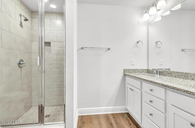 bathroom with hardwood / wood-style flooring, vanity, and walk in shower