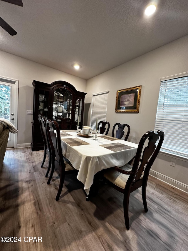 dining room with wood-type flooring, ceiling fan, and a textured ceiling