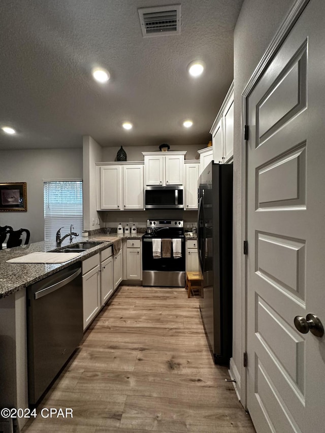 kitchen with sink, stainless steel appliances, light hardwood / wood-style floors, and white cabinets