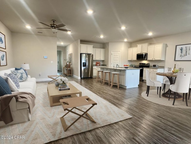 living room featuring hardwood / wood-style flooring, ceiling fan, and sink