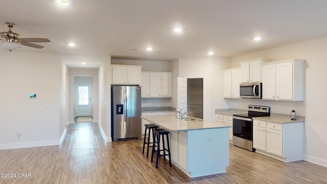 kitchen with white cabinets, appliances with stainless steel finishes, and a center island with sink