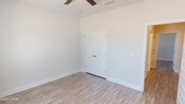 unfurnished bedroom featuring a closet, light hardwood / wood-style floors, and ceiling fan