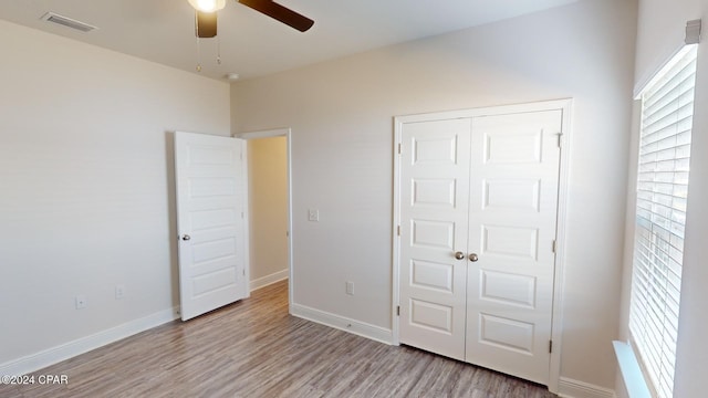 unfurnished bedroom featuring ceiling fan, light hardwood / wood-style floors, and a closet