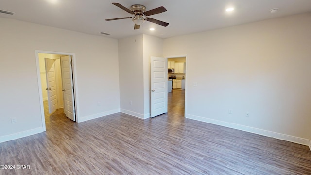 unfurnished bedroom featuring ensuite bath, ceiling fan, and hardwood / wood-style flooring