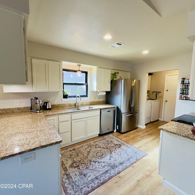 kitchen with white cabinets, sink, independent washer and dryer, light hardwood / wood-style floors, and stainless steel appliances