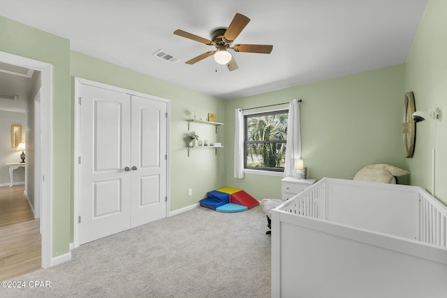 carpeted bedroom with ceiling fan, a closet, and a nursery area