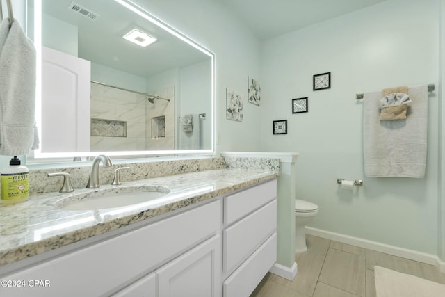 bathroom with a tile shower, vanity, and toilet