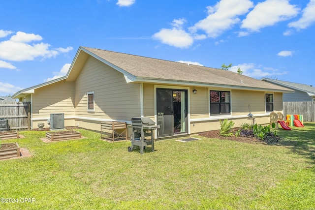 back of house featuring a lawn, a playground, and central air condition unit