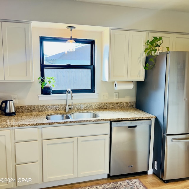 kitchen with white cabinetry, sink, hanging light fixtures, appliances with stainless steel finishes, and light wood-type flooring