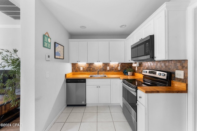 kitchen with white cabinets, stainless steel appliances, and wood counters