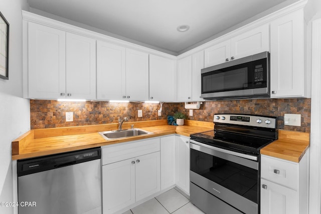 kitchen featuring butcher block counters, white cabinetry, sink, light tile patterned floors, and appliances with stainless steel finishes