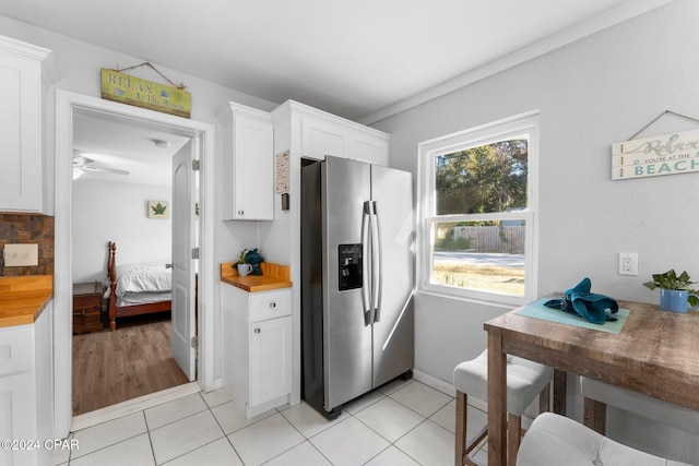 kitchen with butcher block countertops, ceiling fan, white cabinets, and stainless steel refrigerator with ice dispenser