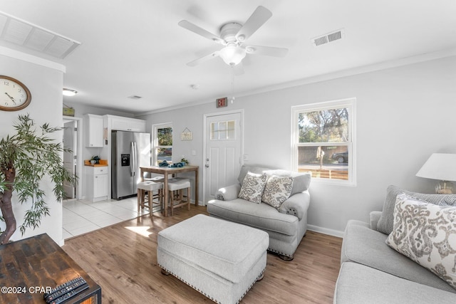 living room with ceiling fan, crown molding, and light wood-type flooring