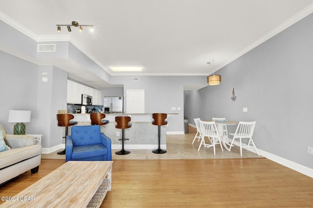 living room with ornamental molding and light hardwood / wood-style floors