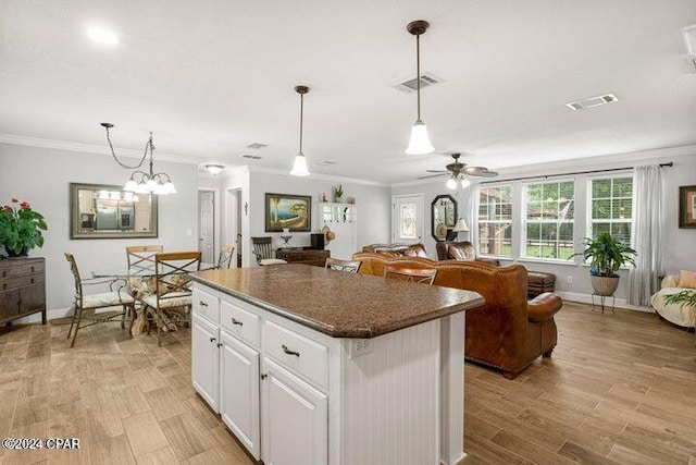 kitchen with white cabinetry, hanging light fixtures, crown molding, and a kitchen island