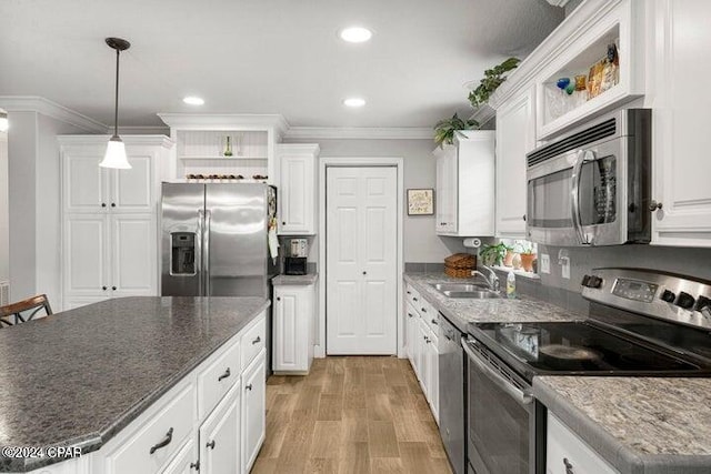 kitchen with appliances with stainless steel finishes, white cabinetry, sink, hanging light fixtures, and light wood-type flooring