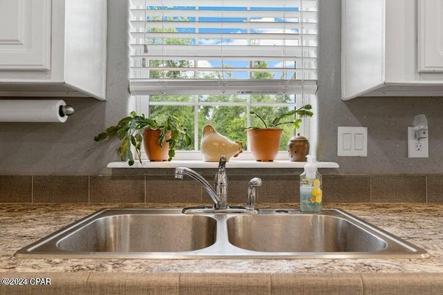 interior details with light stone countertops, sink, white cabinetry, and tasteful backsplash