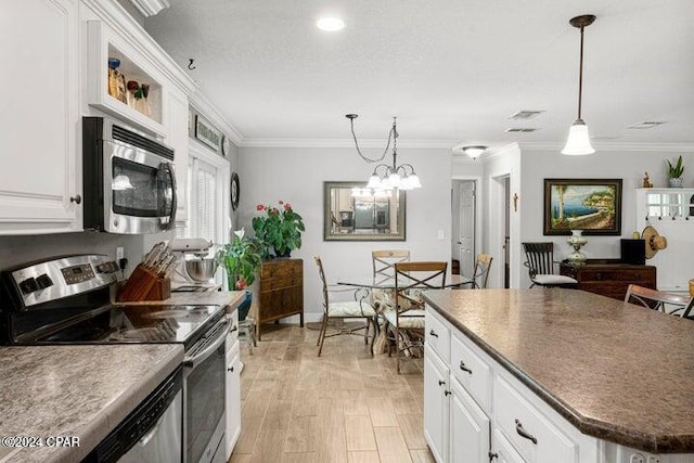 kitchen with white cabinets, pendant lighting, appliances with stainless steel finishes, and a kitchen island