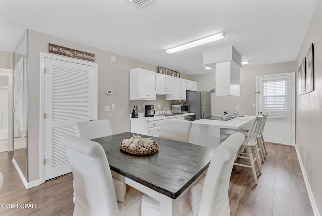 dining room with a textured ceiling, light hardwood / wood-style flooring, and sink