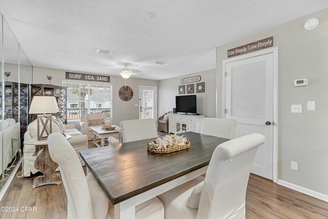 dining room with ceiling fan, wood-type flooring, and a textured ceiling