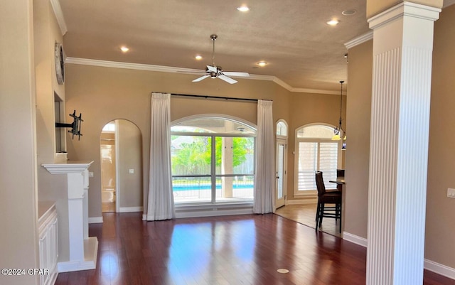 interior space with ceiling fan, crown molding, dark wood-type flooring, and decorative columns