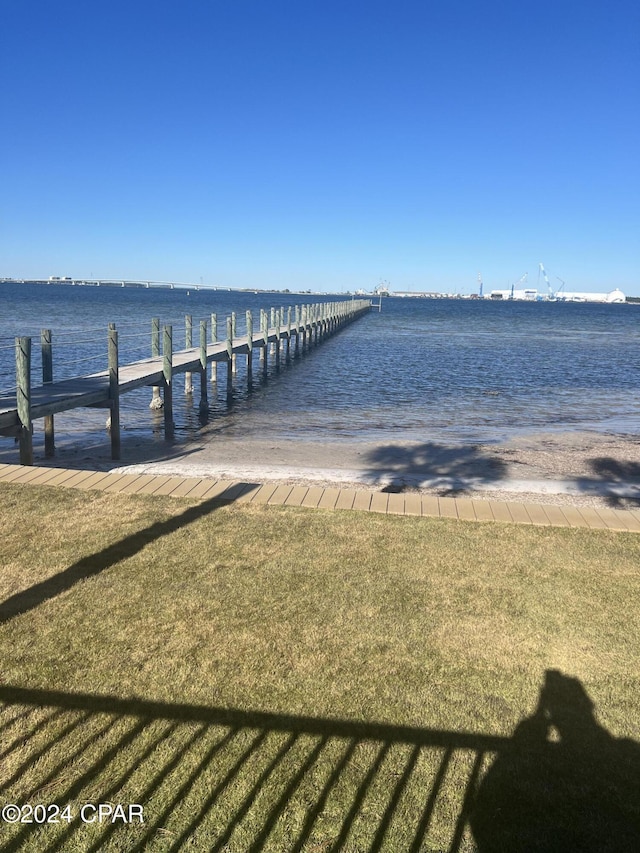 view of dock with a water view and a lawn