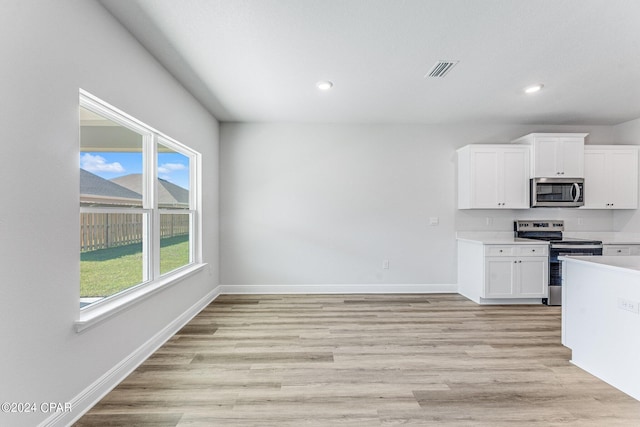 kitchen with appliances with stainless steel finishes, light hardwood / wood-style flooring, and white cabinetry