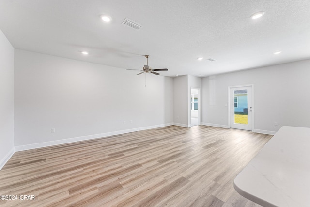 unfurnished living room featuring a textured ceiling, light hardwood / wood-style flooring, and ceiling fan