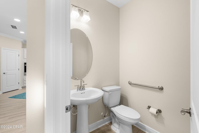 bathroom with visible vents, wood finished floors, baseboards, toilet, and ornamental molding