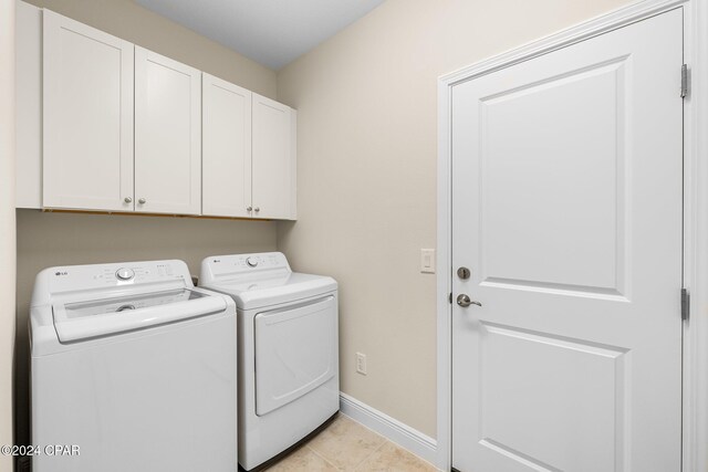 laundry room featuring cabinet space, light tile patterned floors, baseboards, and washer and clothes dryer