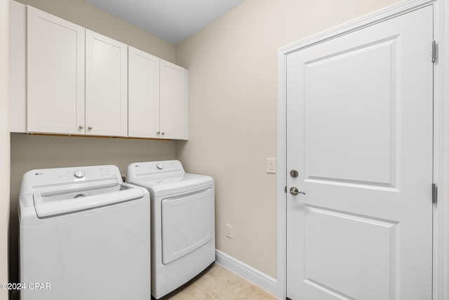 clothes washing area featuring light tile patterned floors, baseboards, cabinet space, and independent washer and dryer