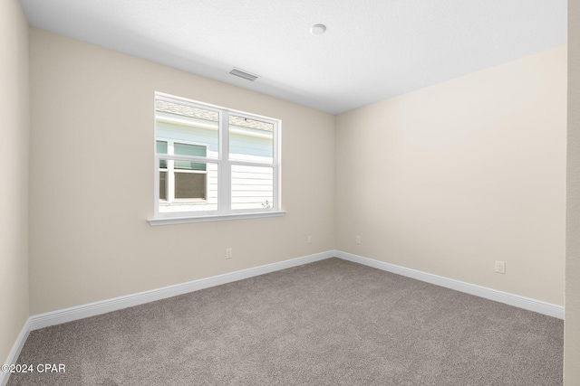 carpeted spare room featuring baseboards and visible vents