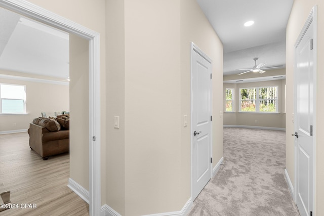 corridor featuring recessed lighting, light wood-style floors, baseboards, and light carpet