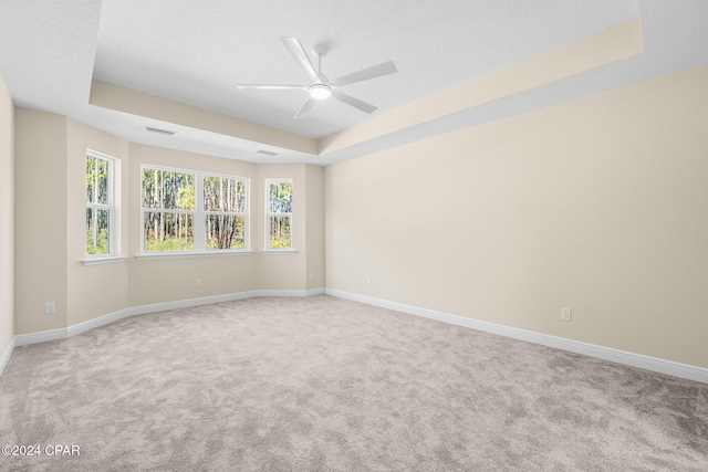 carpeted empty room with baseboards, visible vents, ceiling fan, a textured ceiling, and a raised ceiling