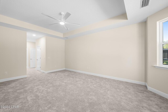 unfurnished room with carpet floors, a raised ceiling, visible vents, and baseboards