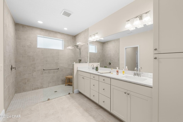 full bathroom with double vanity, a walk in shower, visible vents, and a sink