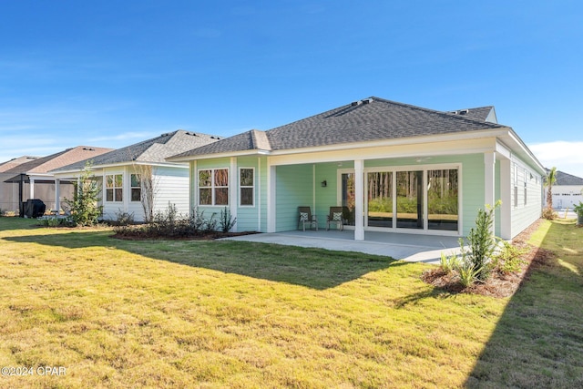 rear view of property featuring a patio area, a lawn, and a shingled roof