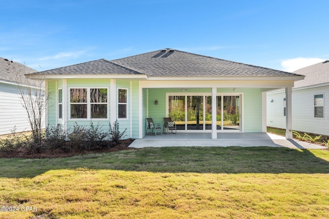 back of property featuring a lawn, a patio, and roof with shingles