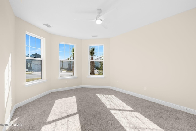 carpeted empty room featuring visible vents, baseboards, and ceiling fan
