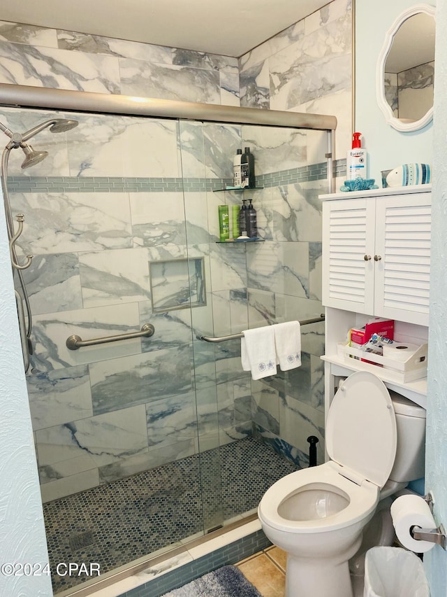 bathroom with tile patterned flooring, toilet, and a shower with shower door