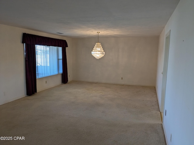 carpeted empty room featuring a chandelier