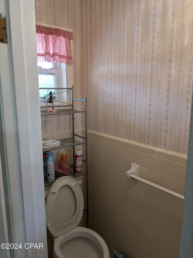 bathroom with toilet and tile walls