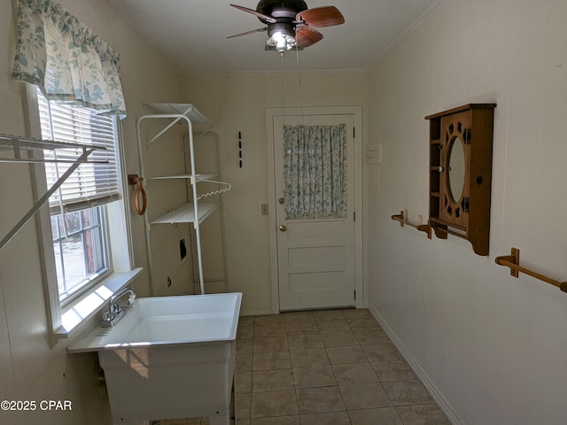 laundry area with ceiling fan, light tile patterned floors, sink, and ornamental molding