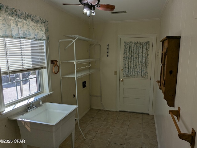 laundry area with ceiling fan, sink, light tile patterned floors, and ornamental molding