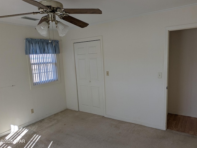 unfurnished bedroom featuring light carpet, a closet, ceiling fan, and crown molding