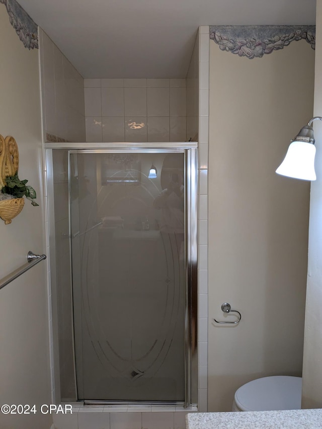 bathroom with toilet and a shower with door