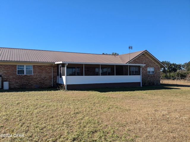 rear view of house featuring a sunroom and a lawn